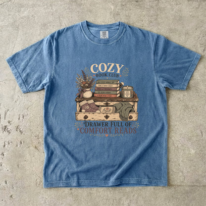 Drawer Full of Comfort Reads reading T-shirt in Blue Jean featuring stacked books, candle, flowers, knitted socks and blankets