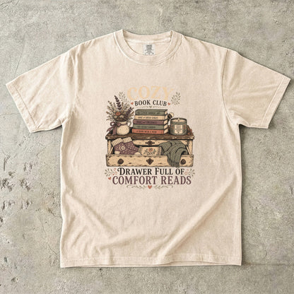 Drawer Full of Comfort Reads reading T-shirt in Ivory featuring stacked books, candle, flowers, knitted socks and blankets