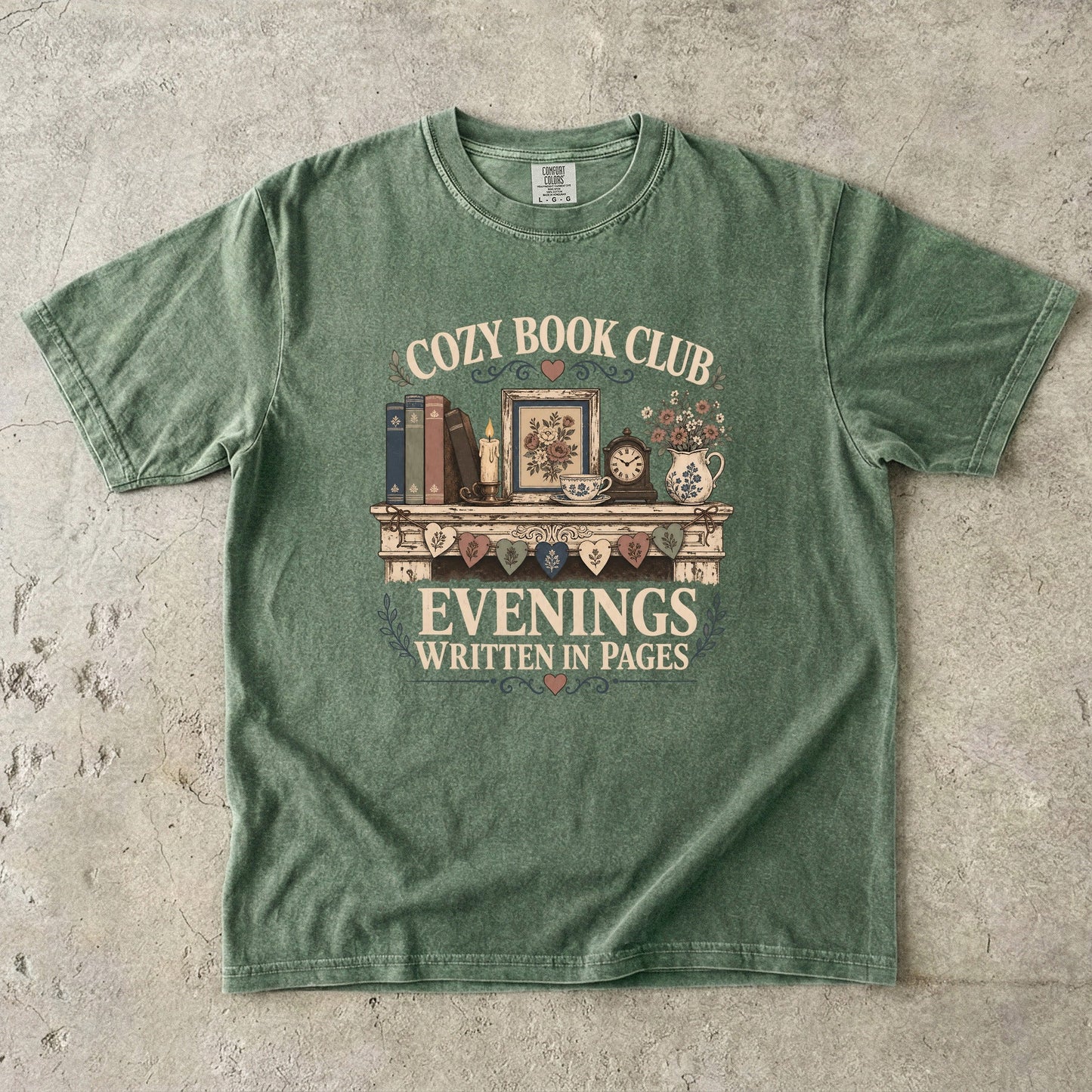 Evenings Written in Pages cozy book club T-shirt in Moss featuring books, a candle, floral teacup, flowers and vintage mantel