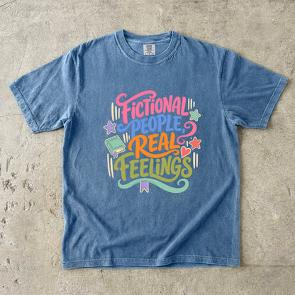 Blue Jean Comfort Colors bookish T-shirt featuring colourful Fictional People, Real Feelings typography with book and heart details.