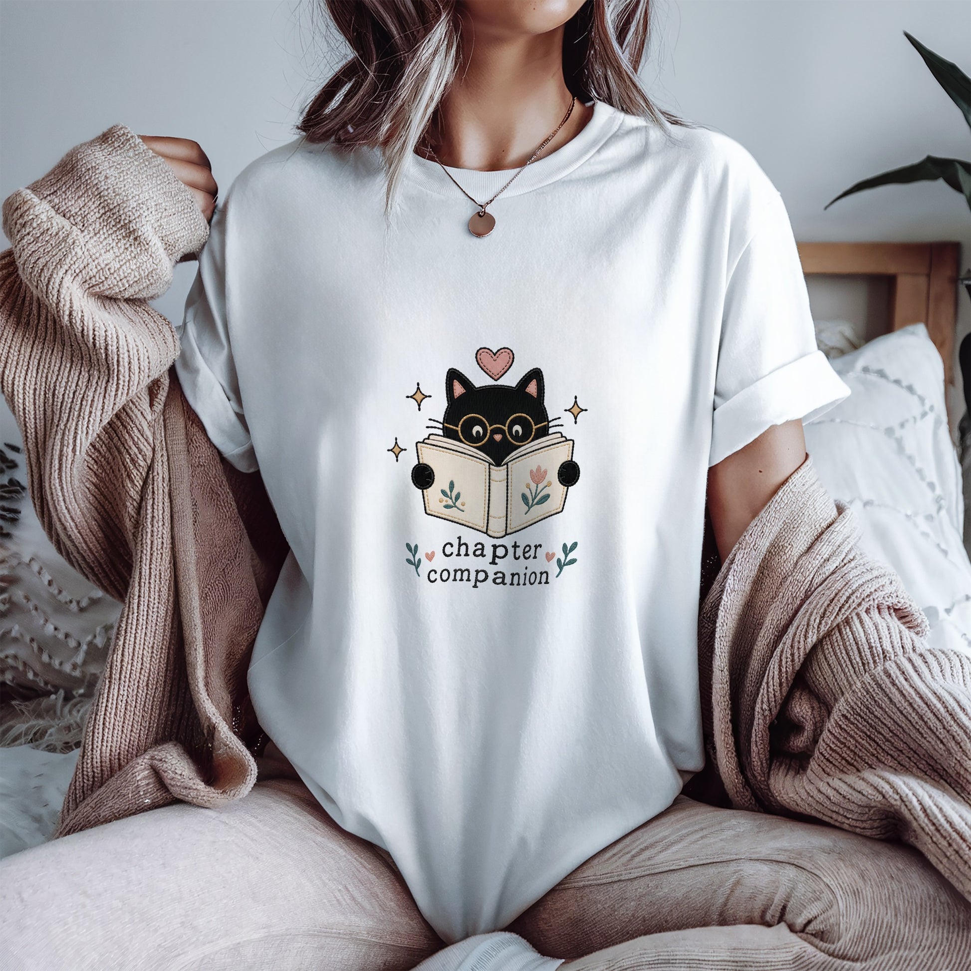 Woman wearing the Chapter Companion book lover cat T-shirt in white by Flourish Creation Labs, a premium Comfort Colors® garment-dyed graphic tee inspired by books, reading and cosy stories.