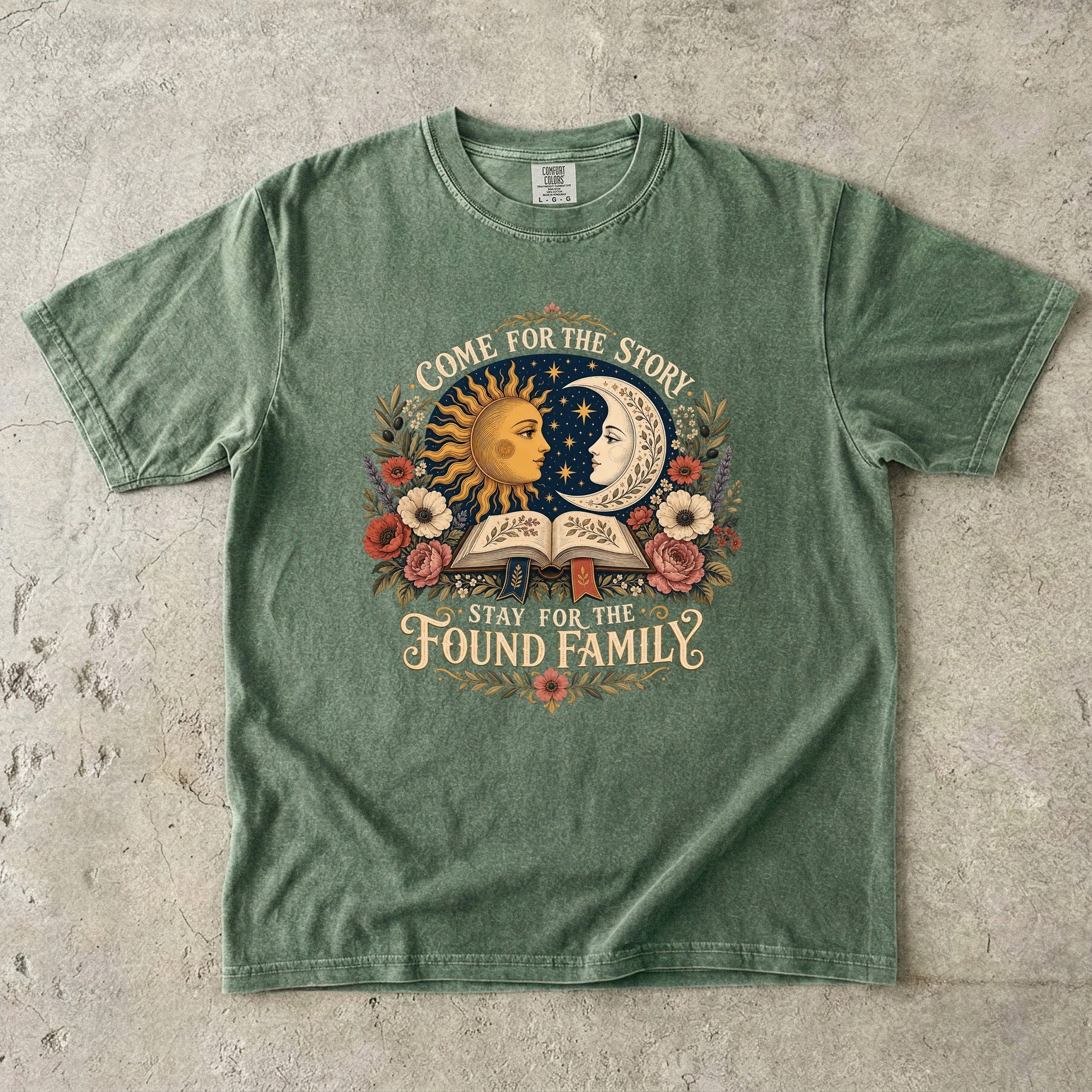 Moss Comfort Colors book lover T-shirt featuring a vintage sun, moon, open book and “Come for the story, stay for the found family” design.