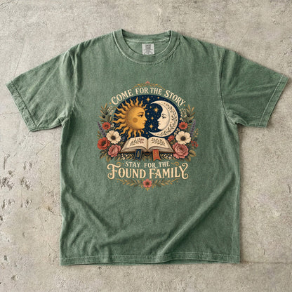 Moss Comfort Colors book lover T-shirt featuring a vintage sun, moon, open book and “Come for the story, stay for the found family” design.