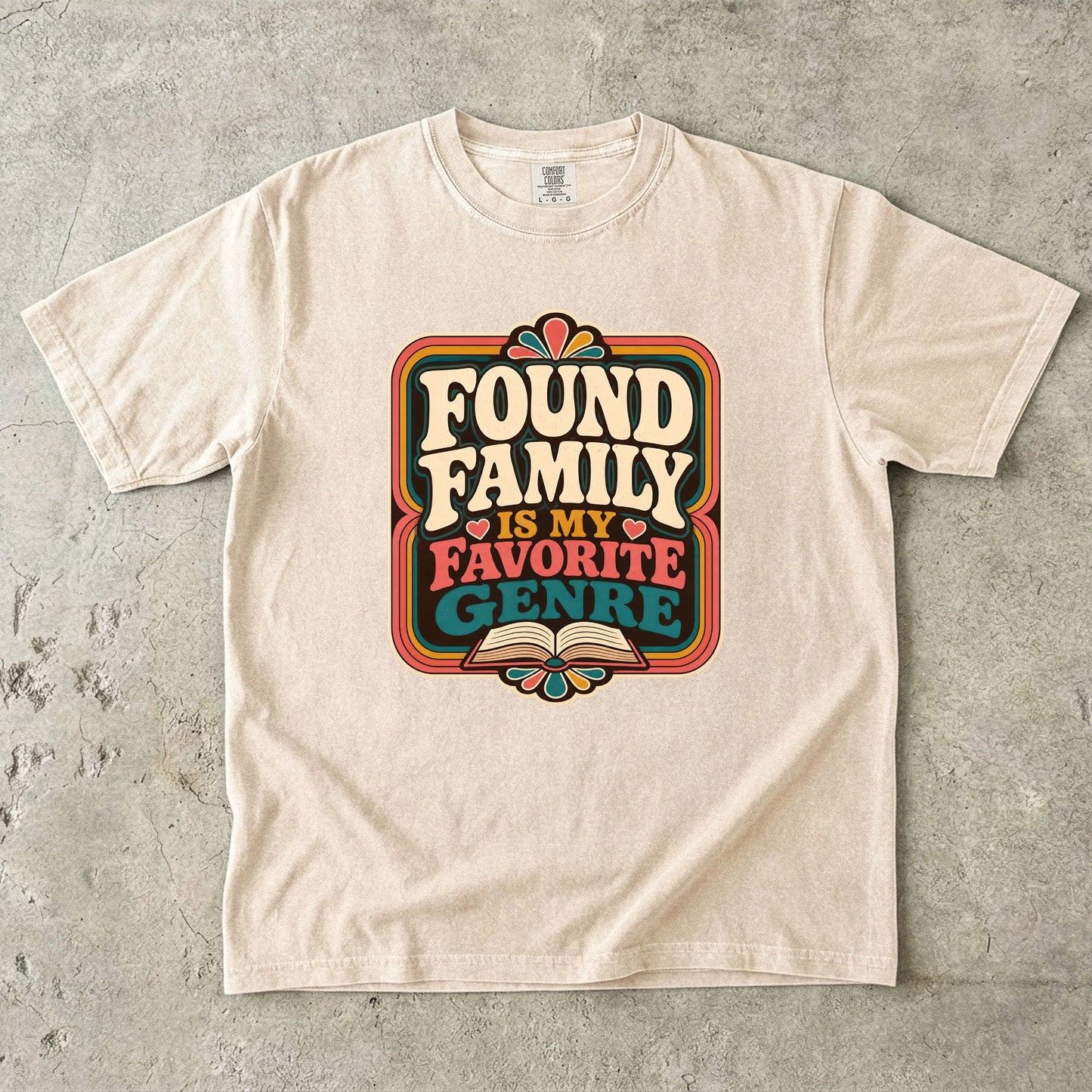 Ivory Comfort Colors found family book shirt featuring colourful retro typography and an open-book illustration.
