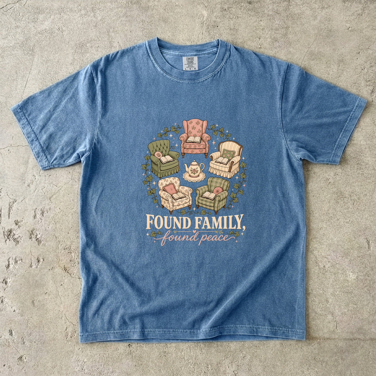 Blue Jean cozy reading T-shirt featuring Found Family, Found Peace with five vintage armchairs, open books, a floral teapot and ivy.