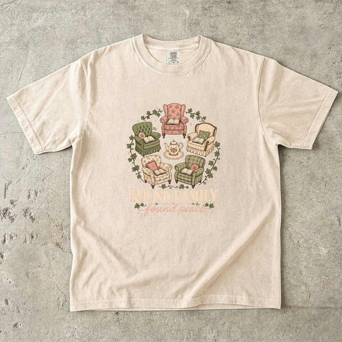 Ivory cozy reading T-shirt featuring Found Family, Found Peace with five vintage armchairs, open books, a floral teapot and ivy.
