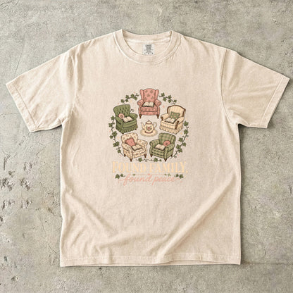 Ivory cozy reading T-shirt featuring Found Family, Found Peace with five vintage armchairs, open books, a floral teapot and ivy.