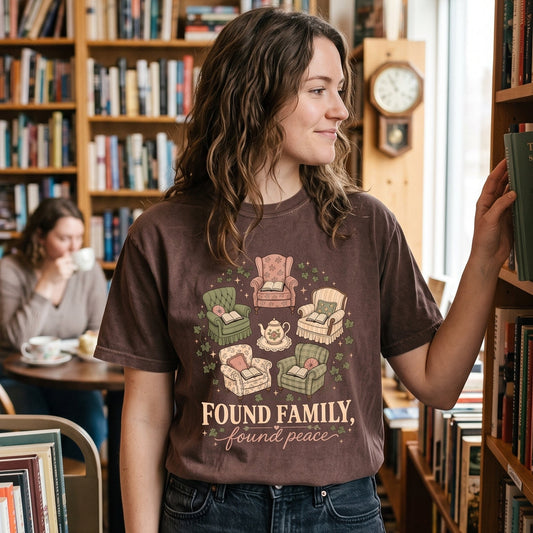Found Family, Found Peace cozy reading T-shirt with vintage armchairs, open books, a floral teapot and trailing ivy artwork.