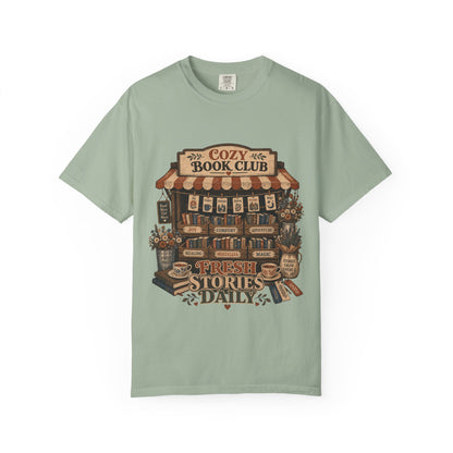 Front view of the Fresh Stories Daily Book Lover Shirt on a Comfort Colors 1717 garment-dyed T-shirt in Bay featuring a cosy book club bookshop design with books, flowers and tea.