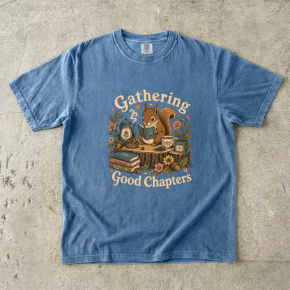 Gathering Good Chapters squirrel reading T-shirt in Blue Jean featuring a squirrel with a book, teapot, teacup, acorns and flowers