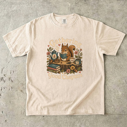 Gathering Good Chapters squirrel reading T-shirt in Ivory featuring a squirrel with a book, teapot, teacup, acorns and flowers