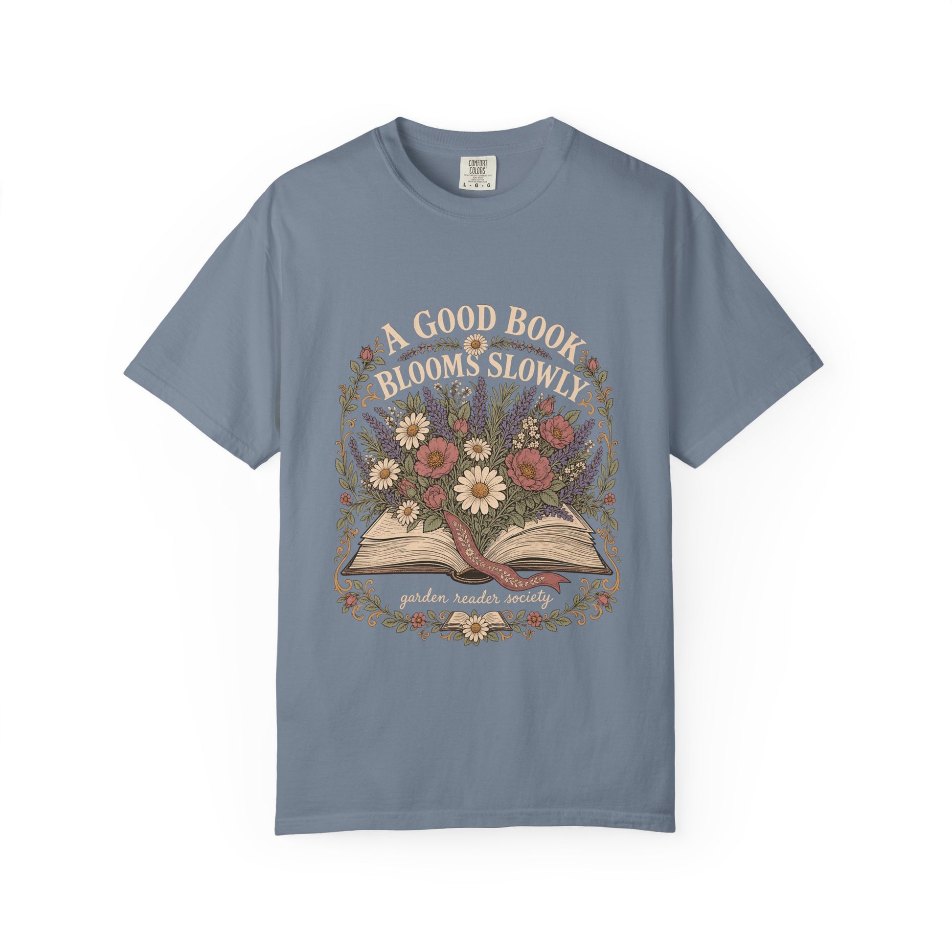 A Good Book Blooms Slowly botanical reading T-shirt with an open book and flowers on Blue Jean.