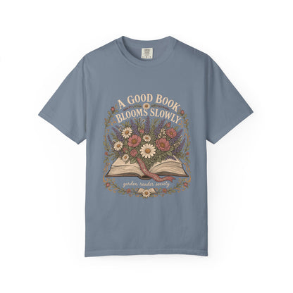 A Good Book Blooms Slowly botanical reading T-shirt with an open book and flowers on Blue Jean.