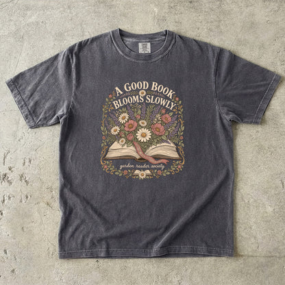 A Good Book Blooms Slowly botanical reading T-shirt with an open book and flowers on Pepper.
