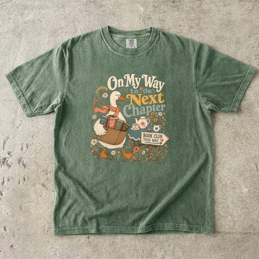 On My Way to the Next Chapter book club T-shirt with goose carrying a basket of books on Moss.