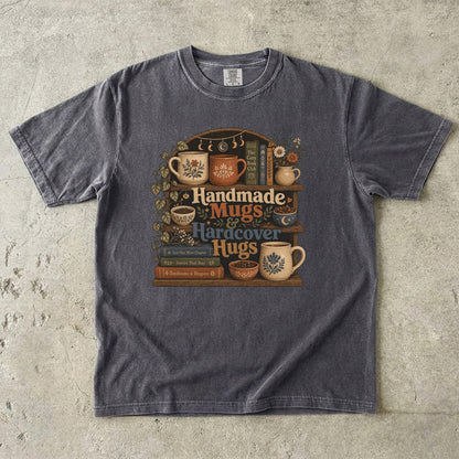Front view of a Pepper Comfort Colors book lover shirt featuring handcrafted pottery, hardcover books and cozy literary artwork.