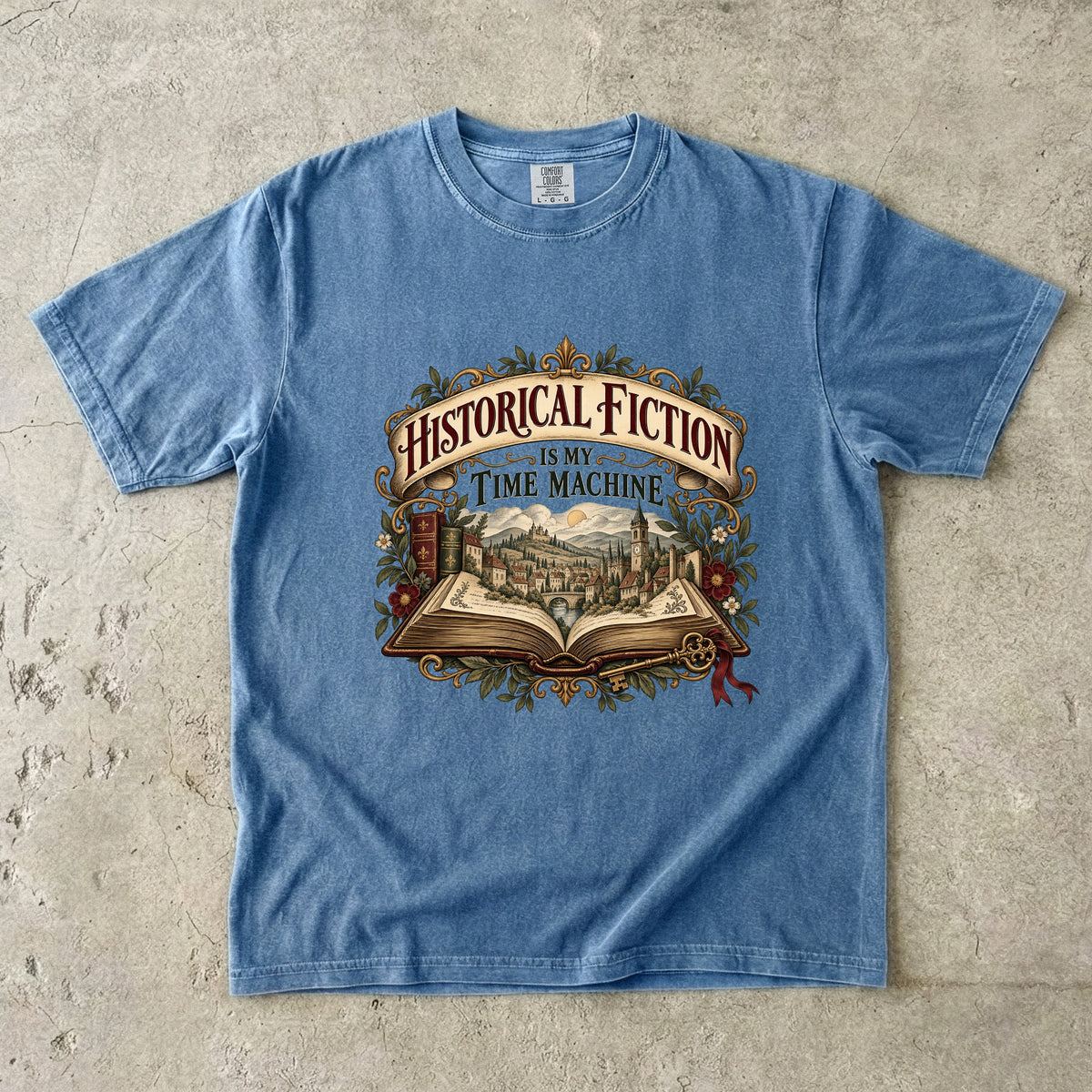 Blue Jean T-shirt featuring “Historical Fiction Is My Time Machine” with an open book revealing an old-world town, ornate gold framing, antique books, leaves and burgundy flowers.