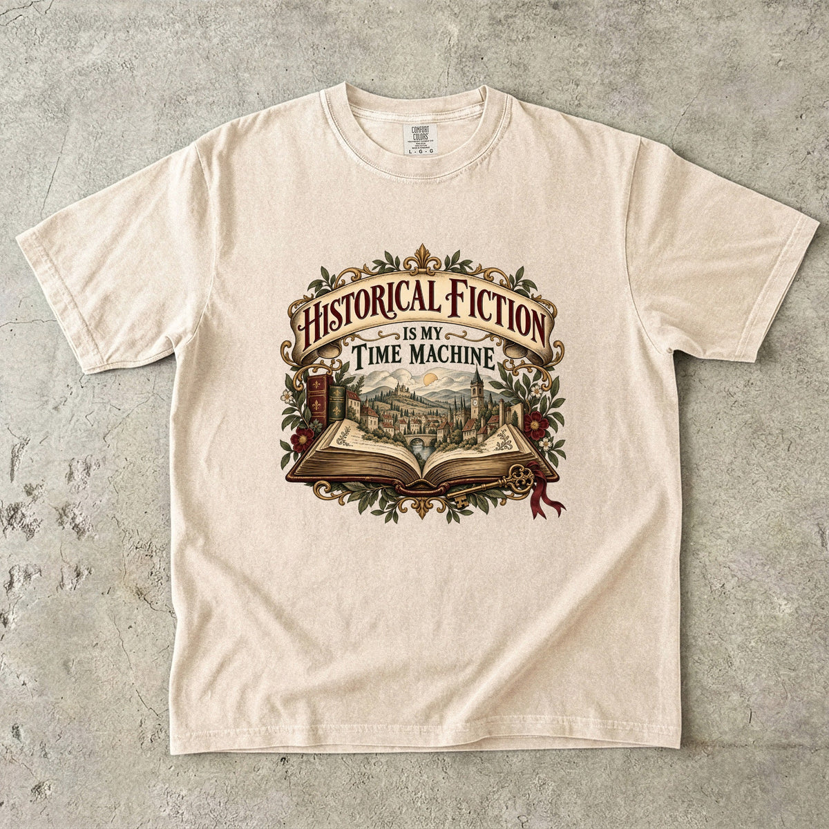 Ivory T-shirt featuring “Historical Fiction Is My Time Machine” with an open book revealing an old-world town, ornate gold framing, antique books, leaves and burgundy flowers.