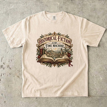 Ivory T-shirt featuring “Historical Fiction Is My Time Machine” with an open book revealing an old-world town, ornate gold framing, antique books, leaves and burgundy flowers.