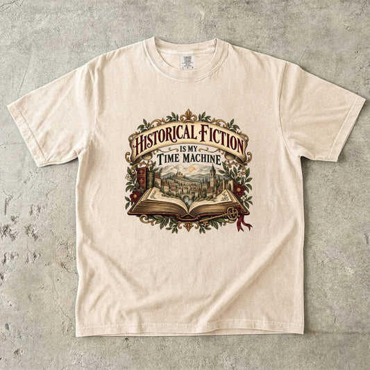 Ivory T-shirt featuring “Historical Fiction Is My Time Machine” with an open book revealing an old-world town, ornate gold framing, antique books, leaves and burgundy flowers.