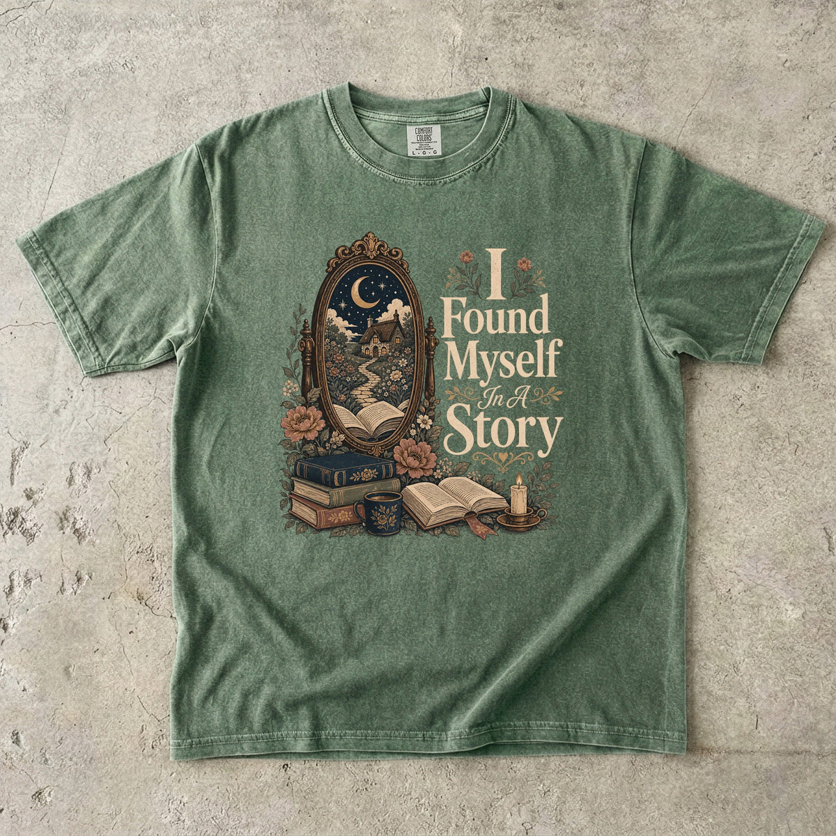 I Found Myself in a Story book lover T-shirt in Moss featuring a moonlit cottage, ornate mirror, open books and flowers