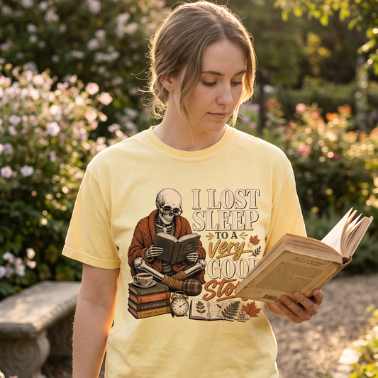 Woman reading outdoors wearing a book lover graphic T-shirt in a woodland setting.