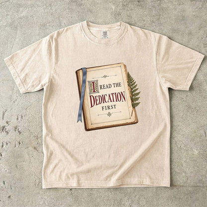 Ivory reader T-shirt with “I Read the Dedication First” inside an illustrated old book