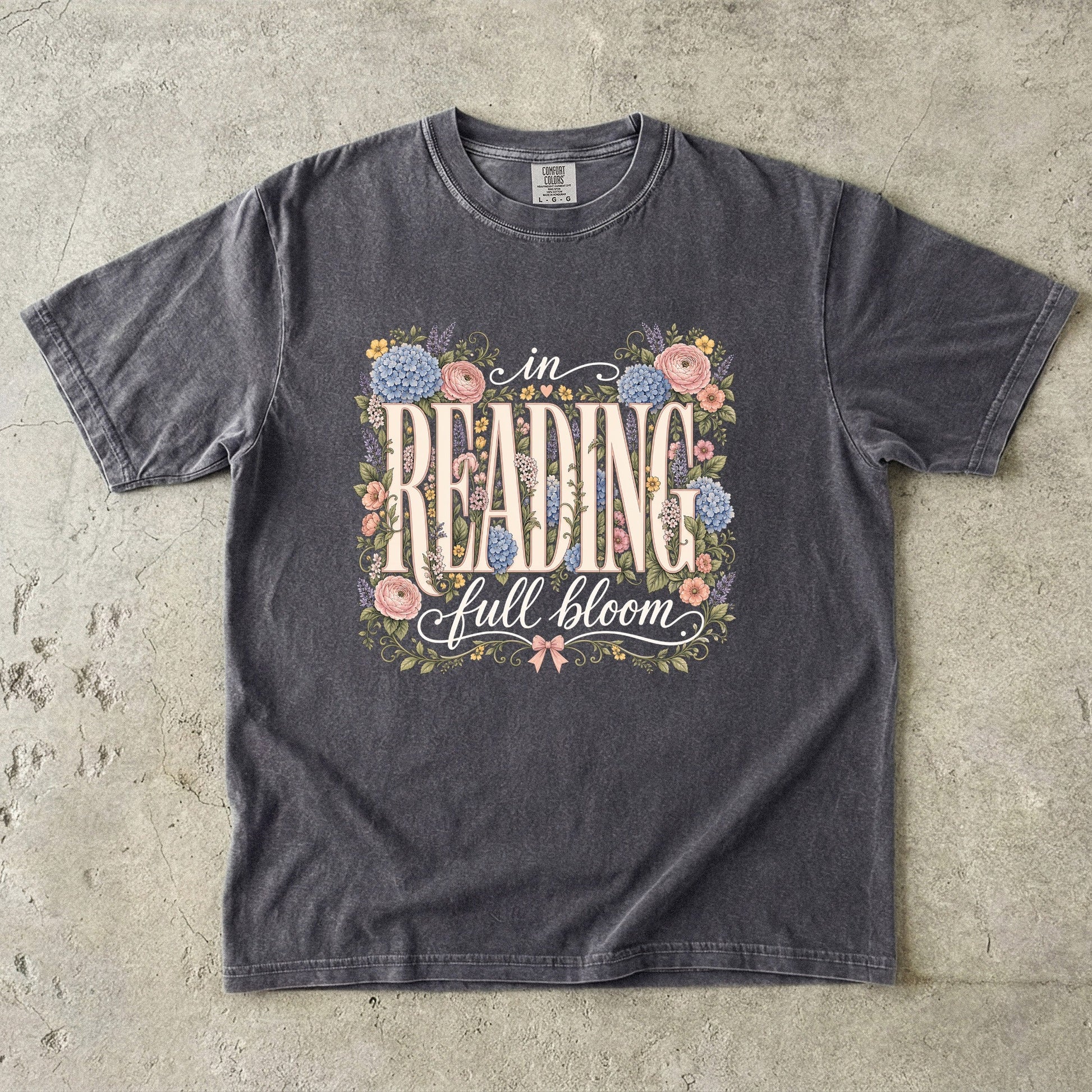 Pepper Comfort Colors book lover T-shirt featuring vintage In Reading, Full Bloom typography surrounded by colourful flowers and greenery.