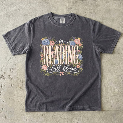 Pepper Comfort Colors book lover T-shirt featuring vintage In Reading, Full Bloom typography surrounded by colourful flowers and greenery.