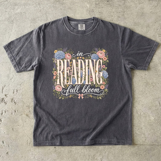 Pepper Comfort Colors book lover T-shirt featuring vintage In Reading, Full Bloom typography surrounded by colourful flowers and greenery.