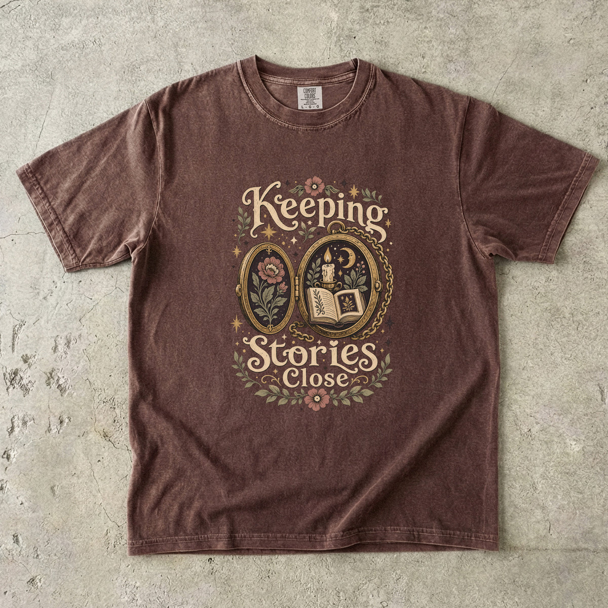 Keeping Stories Close book lover T-shirt in Espresso featuring an ornate locket with an open book, candle, moon and flowers