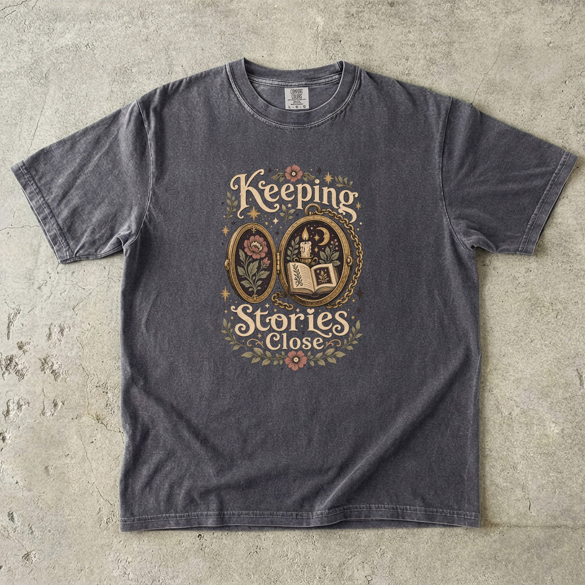 Keeping Stories Close book lover T-shirt in Pepper featuring an ornate locket with an open book, candle, moon and flowers