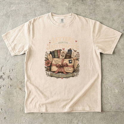 Front view of the Letters From the Last Chapter book club illustration printed on an Ivory Comfort Colors T-shirt. 