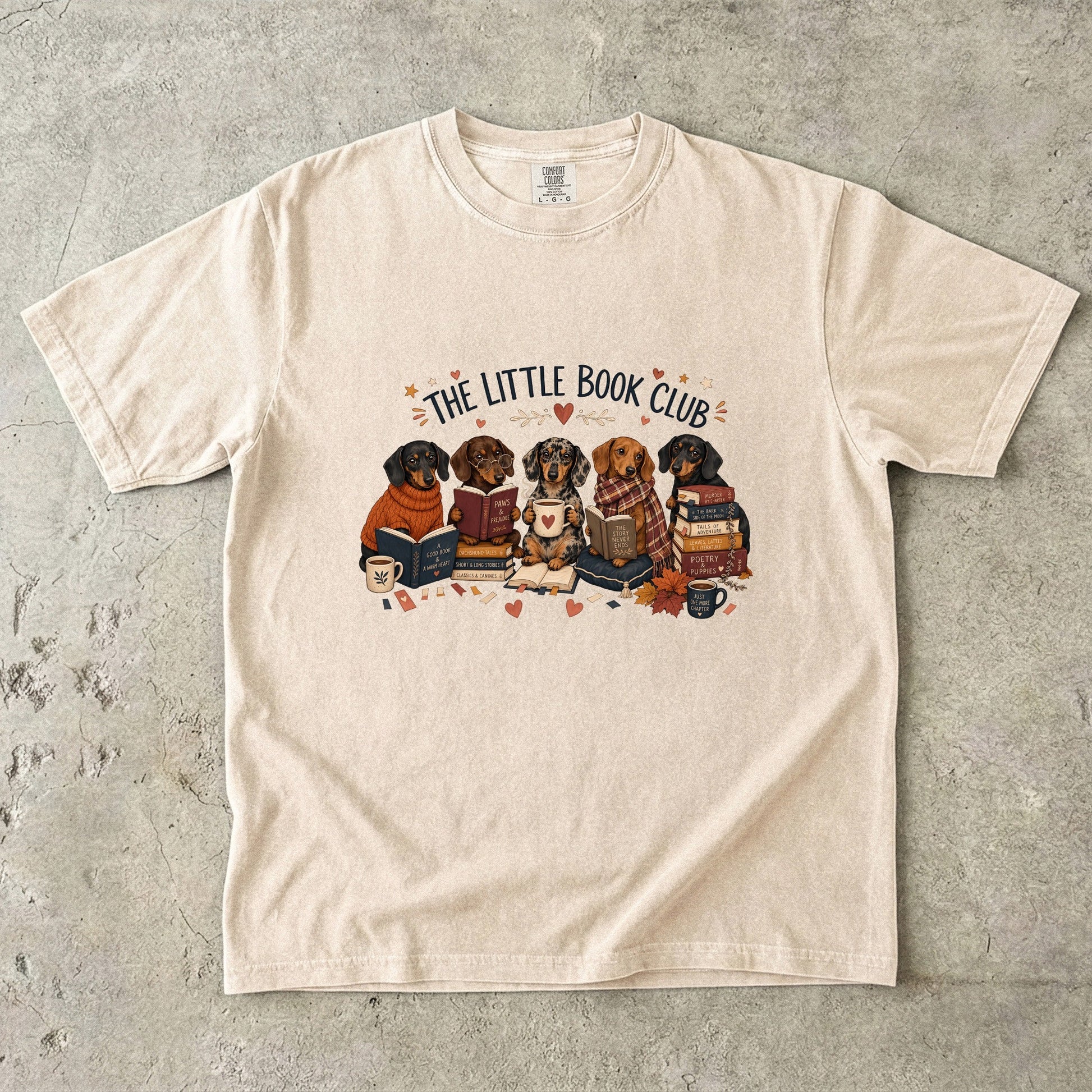 Ivory Comfort Colors dog lover T-shirt featuring dachshunds gathered with books and mugs in The Little Book Club design.