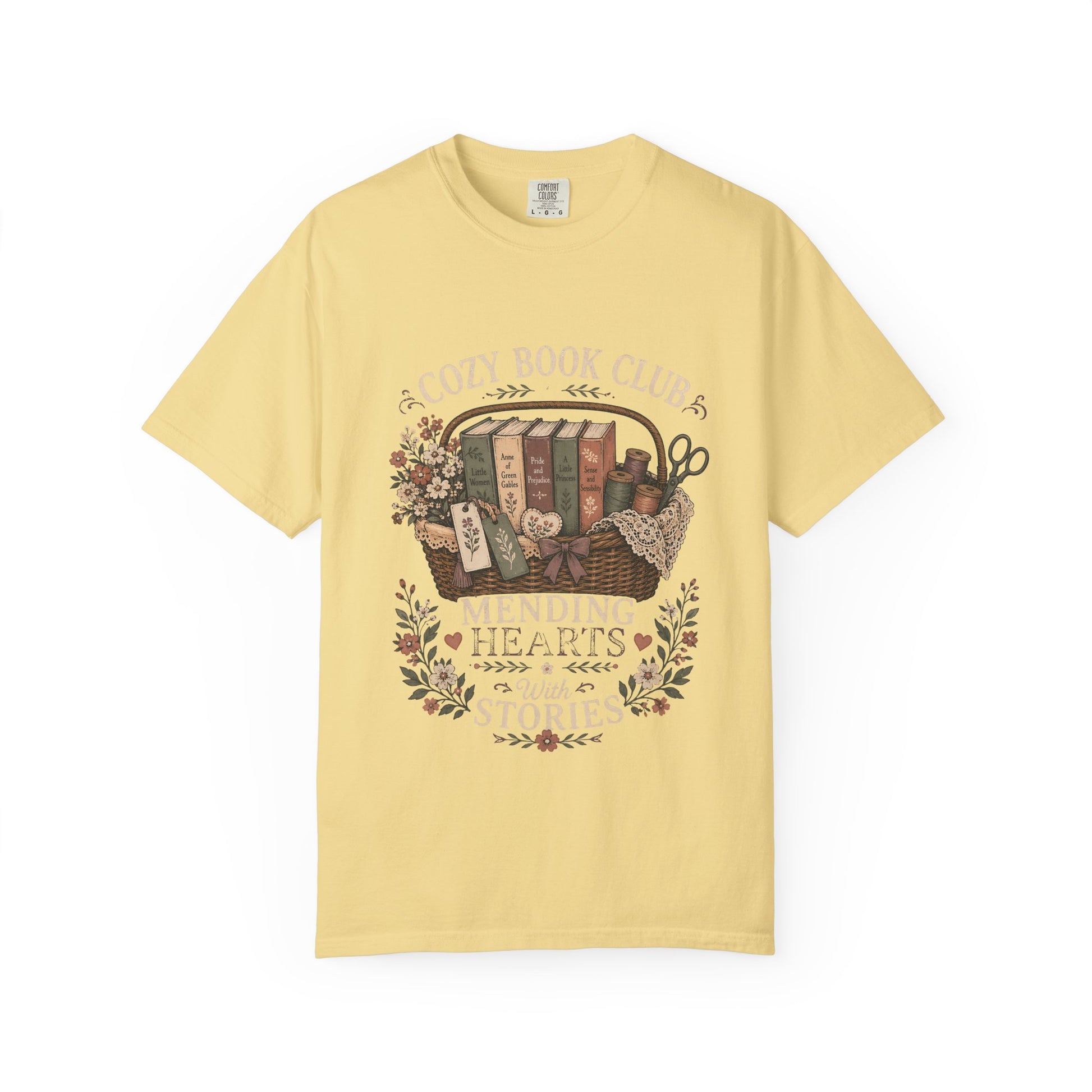 Mending Hearts With Stories book club T-shirt in Butter featuring classic books, sewing notions, flowers and a woven basket