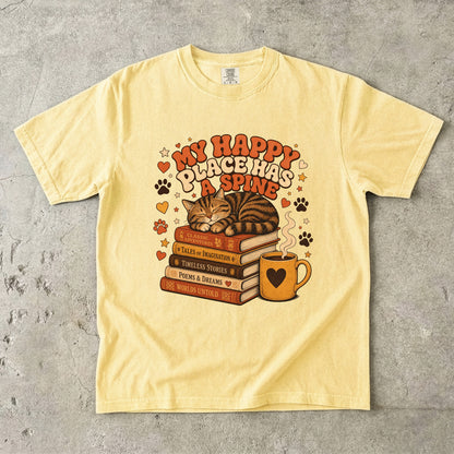 Butter cat book lover T-shirt featuring a sleeping tabby on stacked books beside a steaming mug with hearts, stars and paw prints.