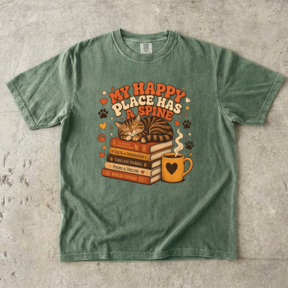 Moss cat book lover T-shirt featuring a sleeping tabby on stacked books beside a steaming mug with hearts, stars and paw prints.