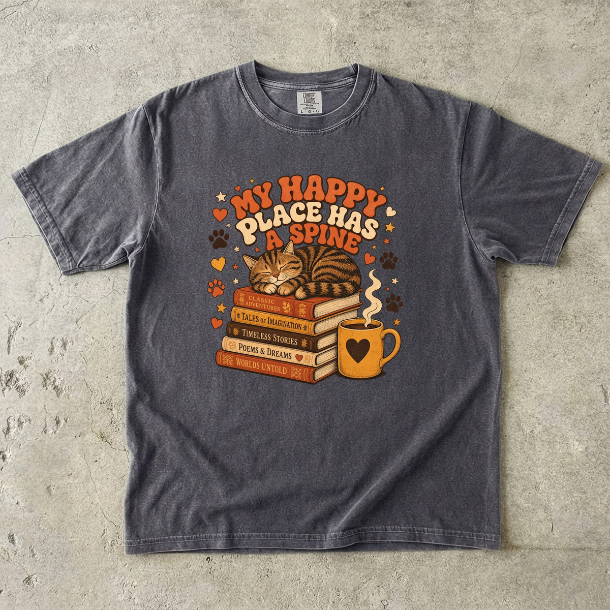 Pepper cat book lover T-shirt featuring a sleeping tabby on stacked books beside a steaming mug with hearts, stars and paw prints.