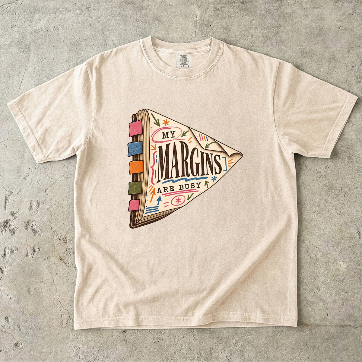 Ivory reading T-shirt with “My Margins Are Busy” on a tabbed book with colourful annotations