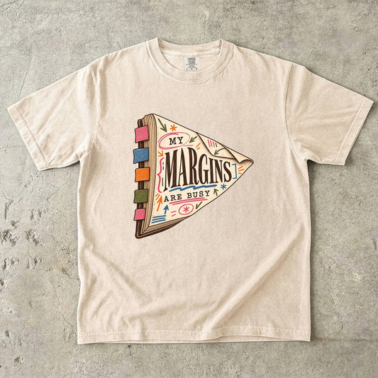 Ivory reading T-shirt with “My Margins Are Busy” on a tabbed book with colourful annotations
