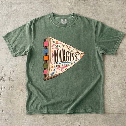 Moss reading T-shirt with “My Margins Are Busy” on a tabbed book with colourful annotations