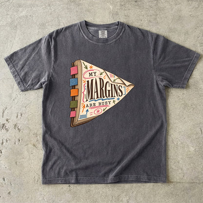 Pepper reading T-shirt with “My Margins Are Busy” on a tabbed book with colourful annotations