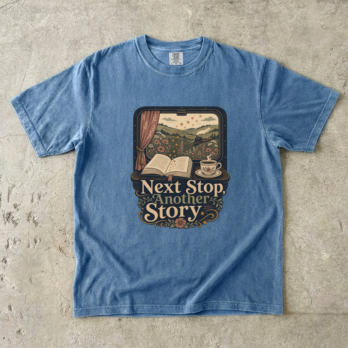 Next Stop, Another Story reading T-shirt in Blue Jean featuring a countryside steam train, open book and floral teacup