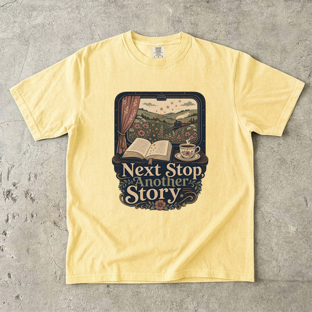 Next Stop, Another Story reading T-shirt in Butter featuring a countryside steam train, open book and floral teacup