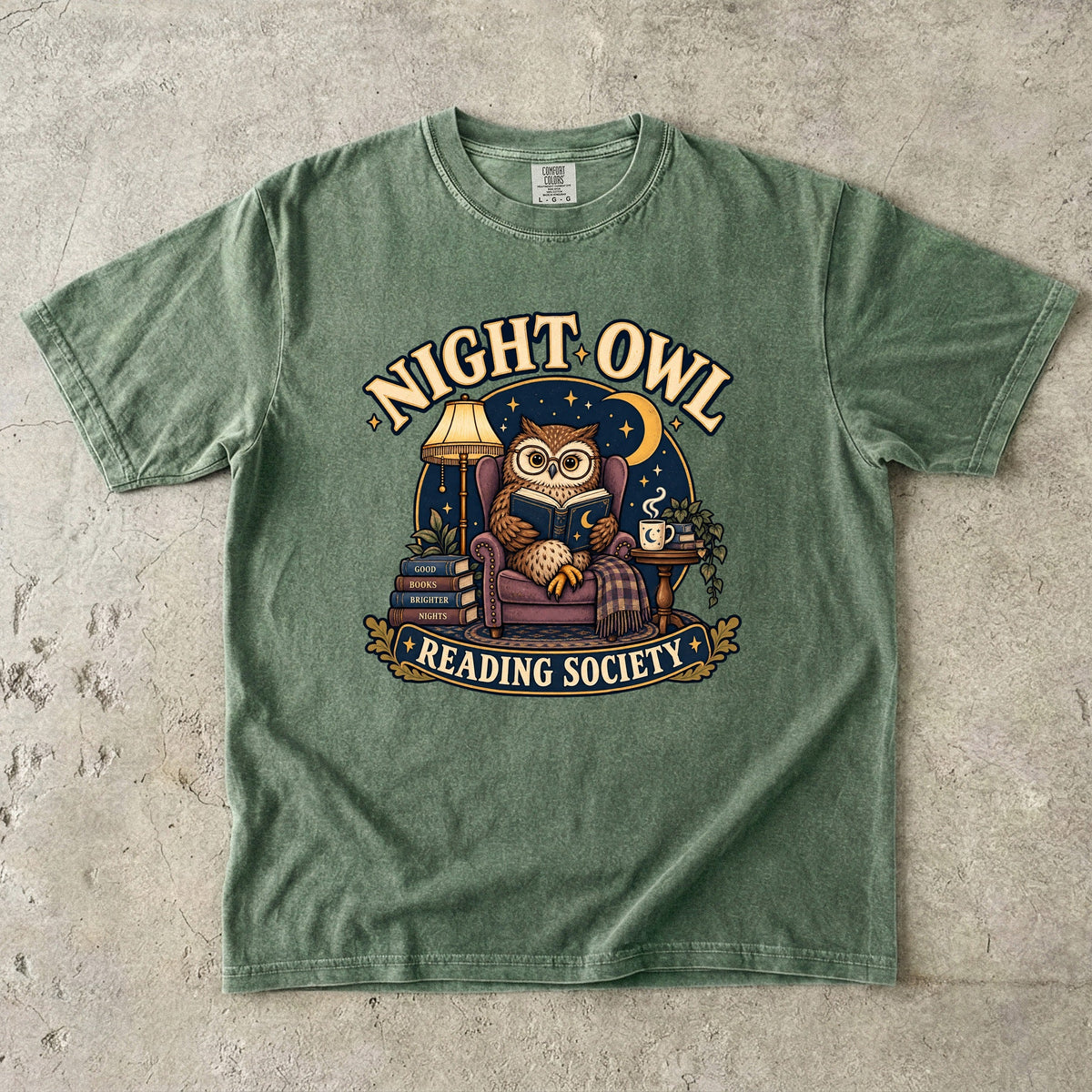 Moss T-shirt featuring “Night Owl Reading Society” with a spectacled owl reading in an armchair, a lamp, books, mug, crescent moon and stars.