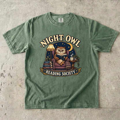 Moss T-shirt featuring “Night Owl Reading Society” with a spectacled owl reading in an armchair, a lamp, books, mug, crescent moon and stars.