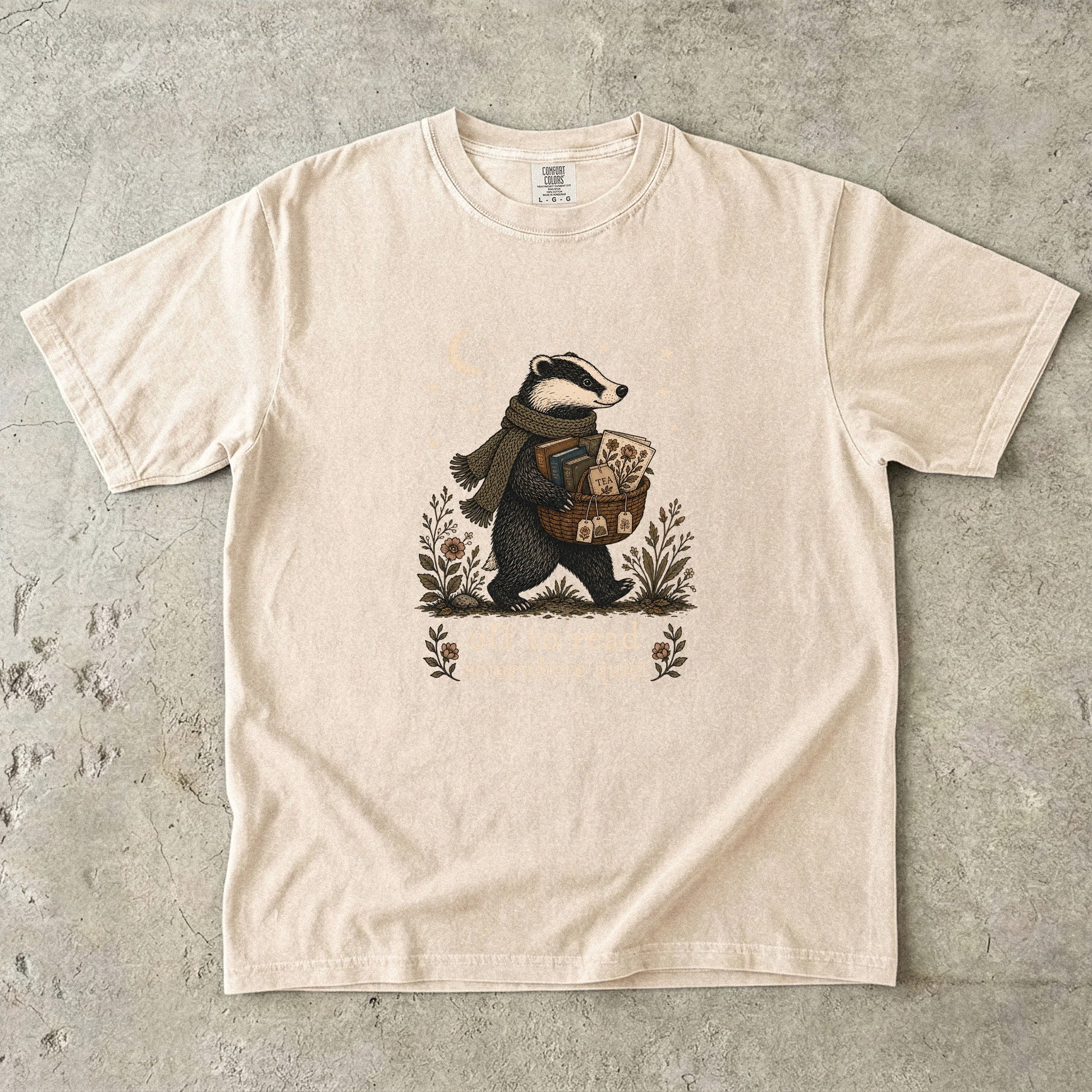 Off to Read Somewhere Quiet badger reading T-shirt in Ivory featuring a scarfed badger carrying books and tea