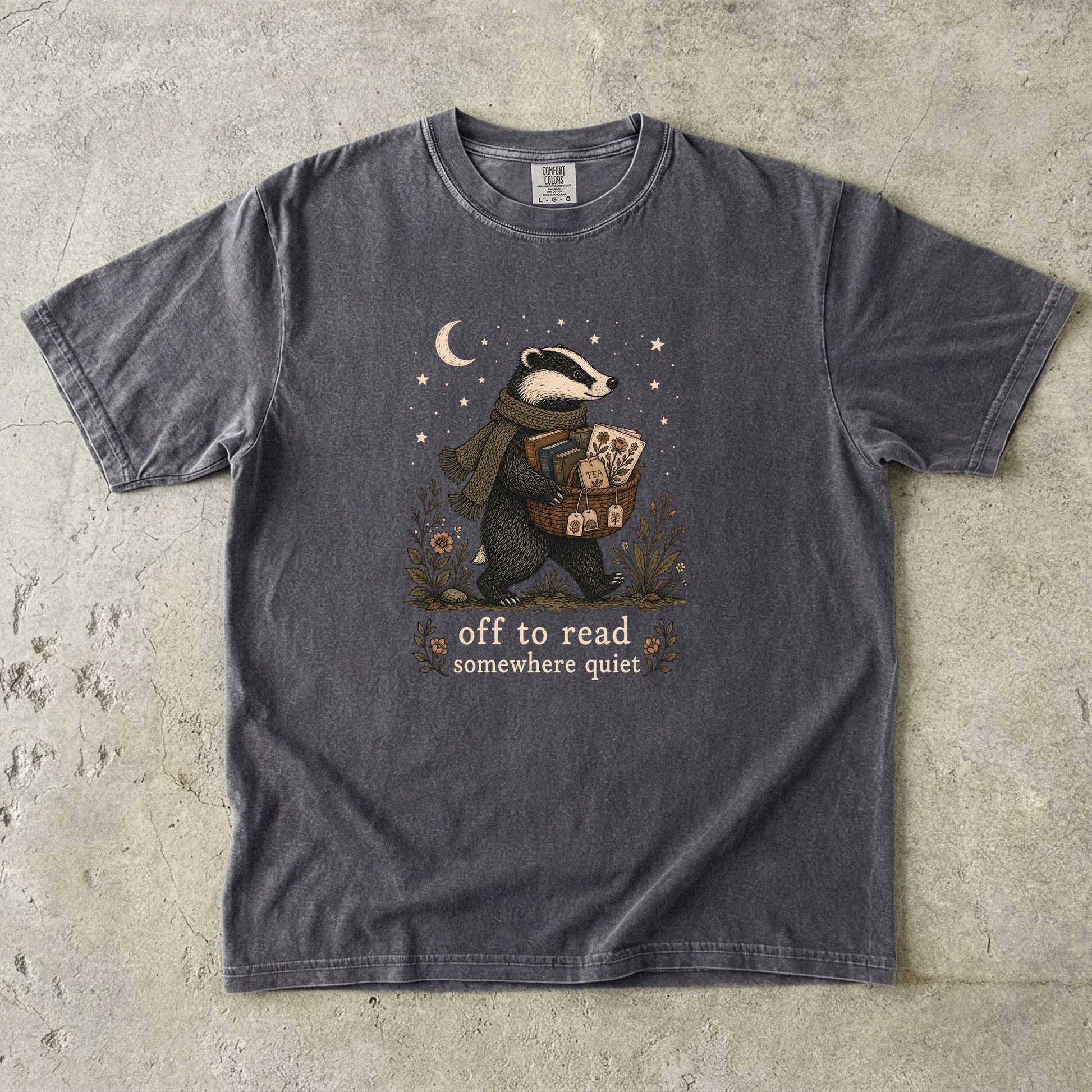 Off to Read Somewhere Quiet badger reading T-shirt in Pepper featuring a scarfed badger carrying books and tea