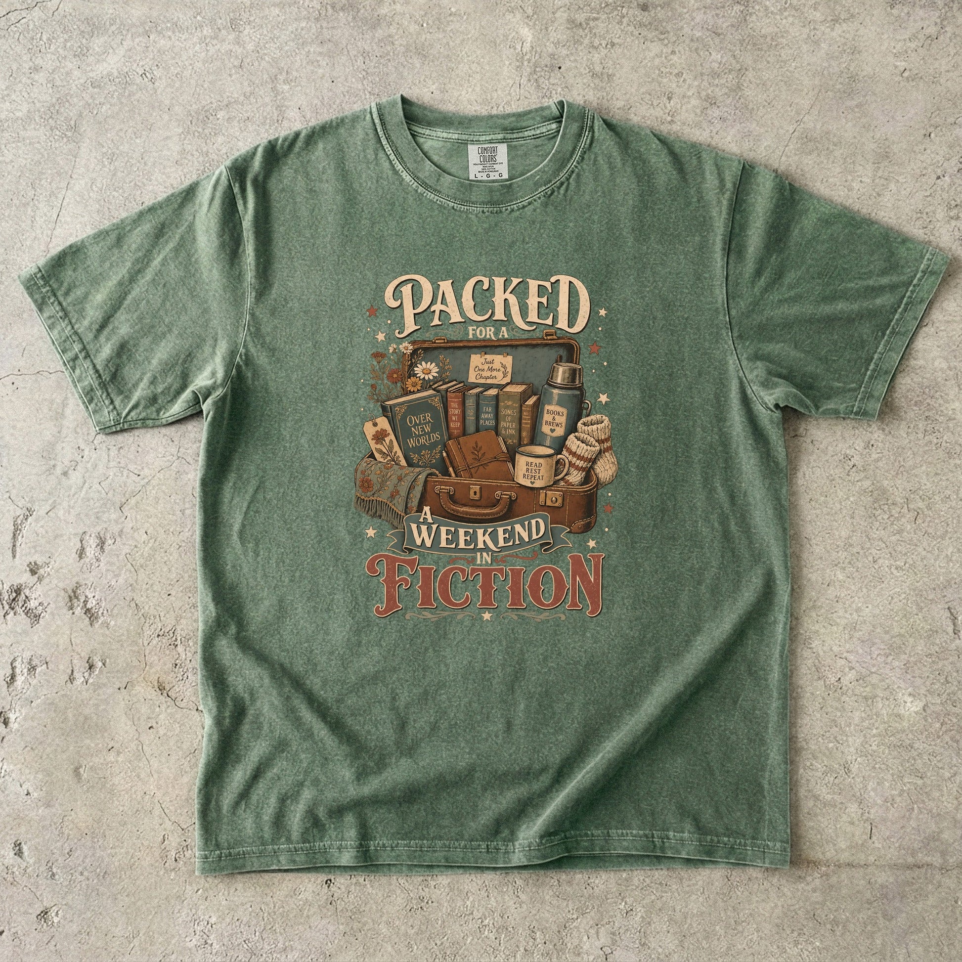 Packed for a Weekend in Fiction reading T-shirt in Moss featuring a vintage suitcase packed with books, a mug, thermos and cozy socks