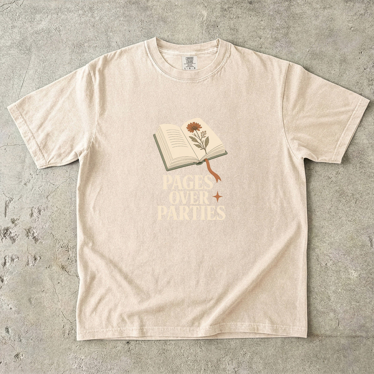 Pages Over Parties introvert reader shirt in Ivory featuring an open book, flower and bold book lover statement.